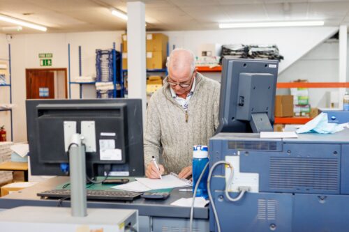 A print operator checking print quality and demonstrating the trustworthiness and reliability needed when choosing a commercial printing company.