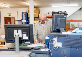 A print operator checking print quality and demonstrating the trustworthiness and reliability needed when choosing a commercial printing company.